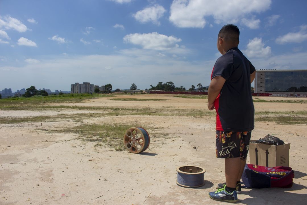 Jovem empina pipa no terreno conhecido como “Estandão”, com o prédio da Unifesp em construção ao fundo, à direita. Foto: Mateus Fernandes