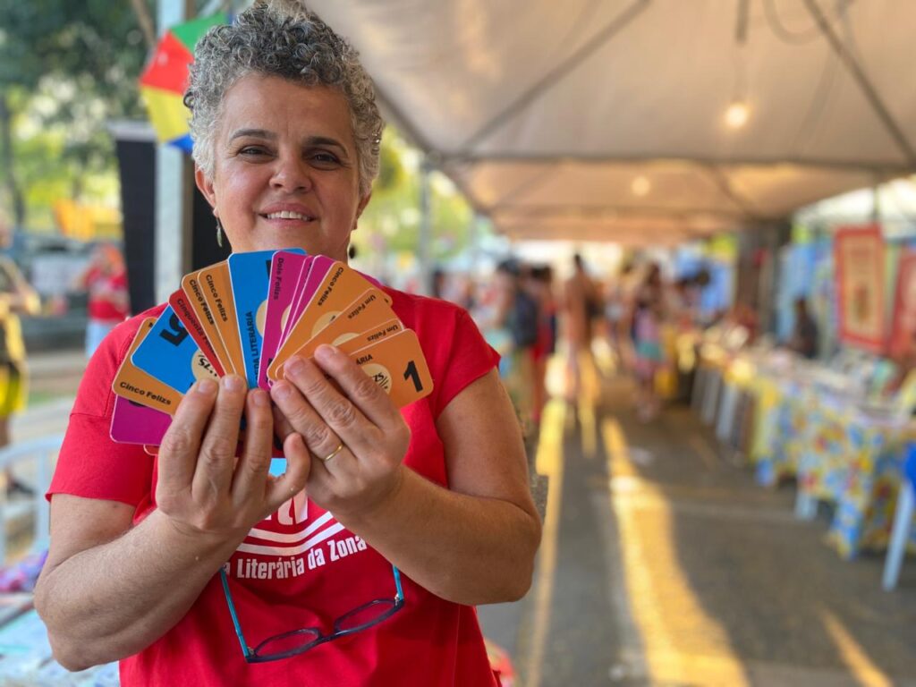 Suzi Soares, produtora cultural segurando cédulas da Moeda Literária durante a Feira Literária da Zona Sul. Foto: Thais Siqueira.